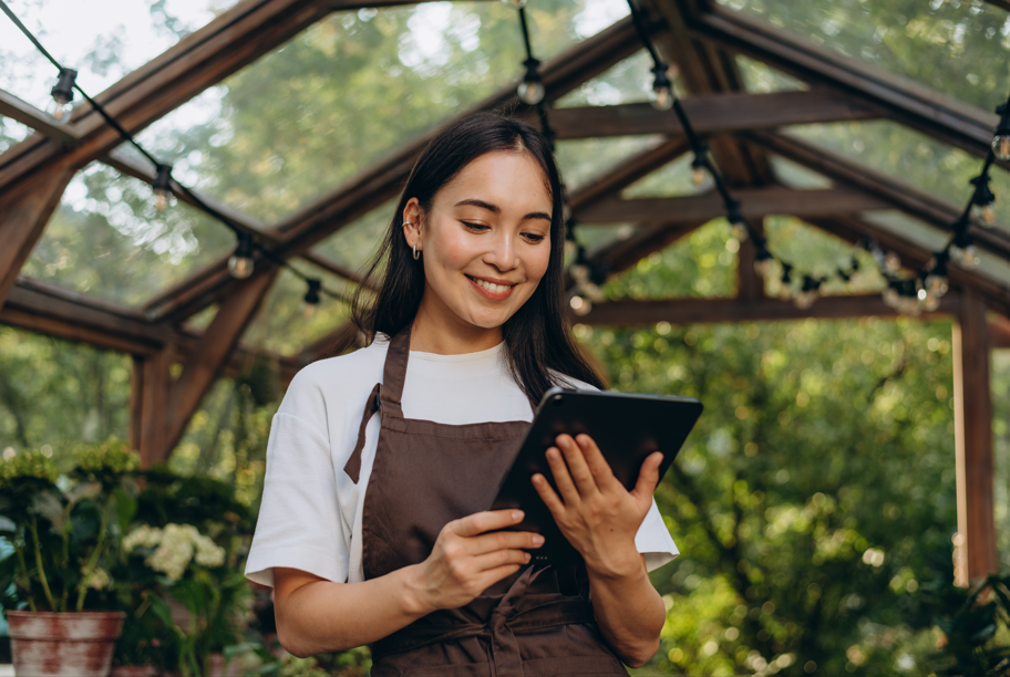 Female business owner holding a tablet standing in a greenhouse Female business owner holding a tablet standing in a greenhouse