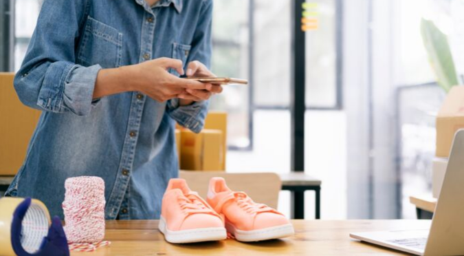 Using mobile with pink shoes on desk.