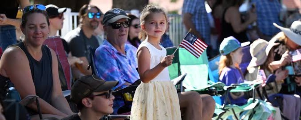 niña pequeña con bandera americana en un desfile