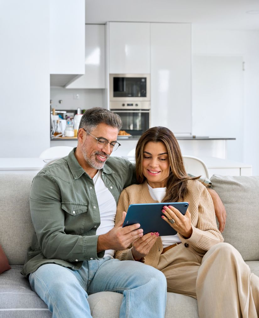 una pareja sentada en el sofá mirando una tablet