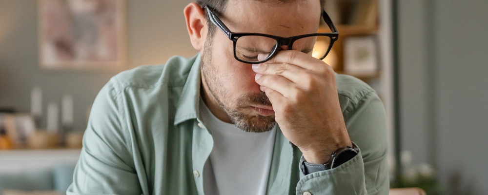 worried concerned young male with glasses rubbing his nose