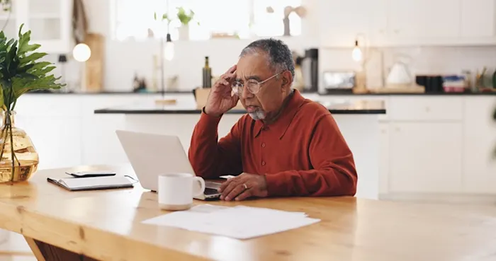 older minority male staring at a computer with a worried look