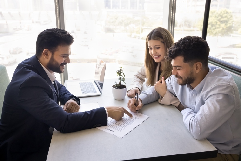 couple sitting with advisor signing agreement couple sitting with advisor signing agreement