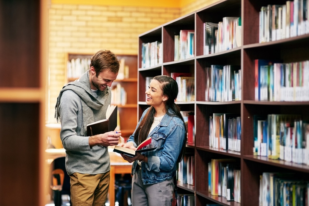 hombre y mujer sonriendo y riendo en biblioteca hombre y mujer sonriendo y riendo en biblioteca