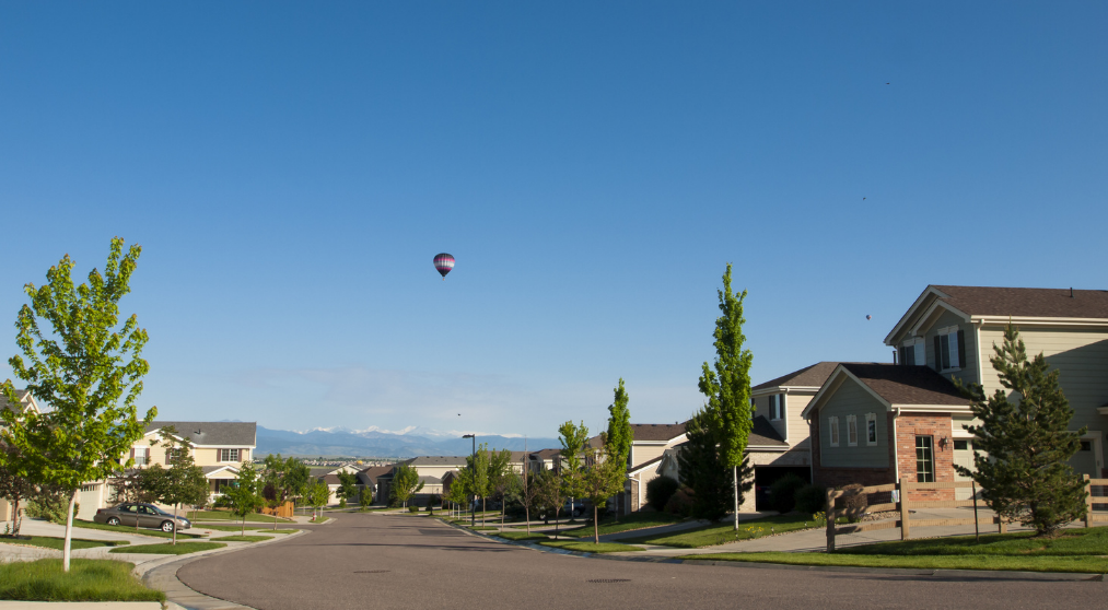 Hot air balloon flying over houses. 