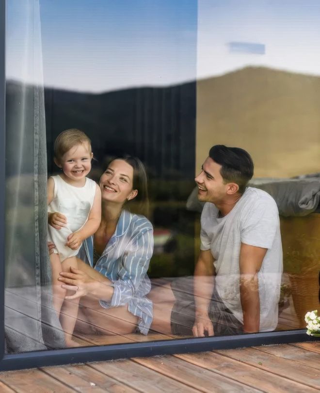 Family happily lounging in their home by a window