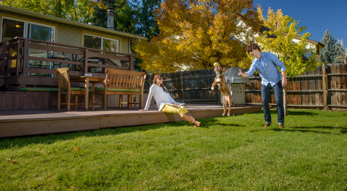 Young couple playing with a dog in the backyard