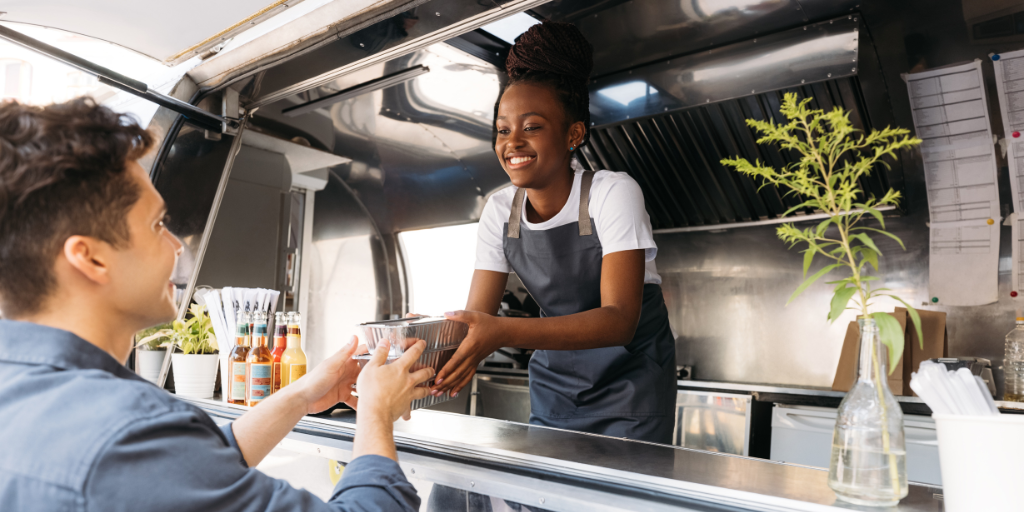 female minority small business owner of a food truck serving a customer